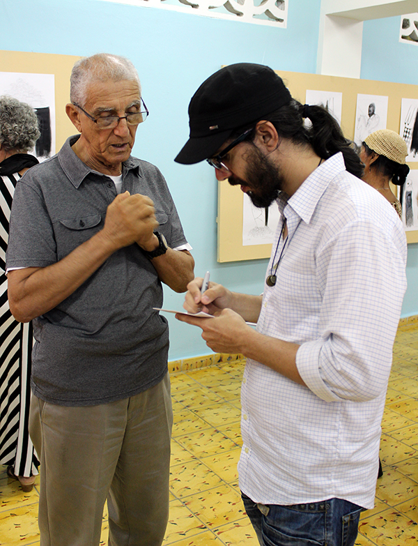 Adrián Sancho (derecha) le autografía una de sus ilustraciones al Rev. Raimundo García Franco