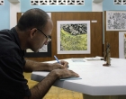 Alexei Gómez firma catálogos para los asistentes