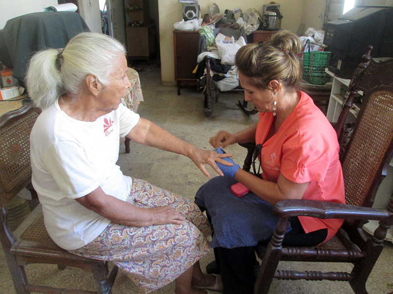 Asistente realizando el servicio de manicura a una beneficiaria