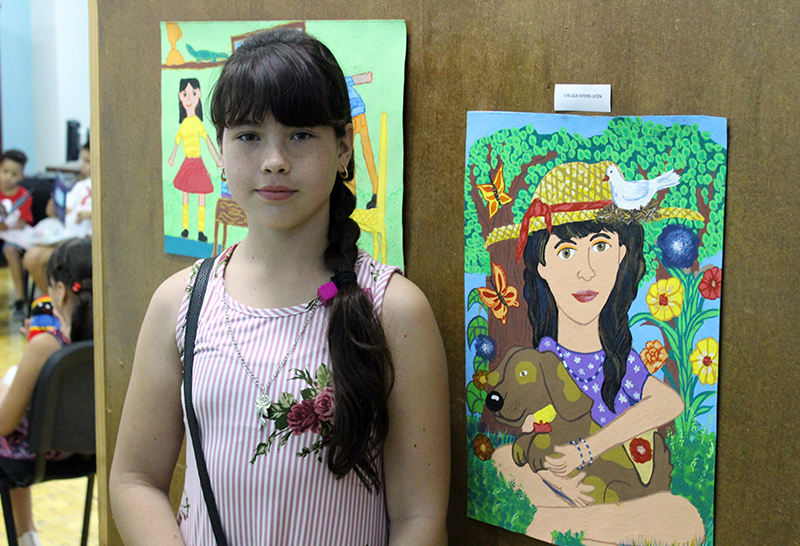 Chelsea Otero León, primer premio del concurso Doña Natura y yo posa junto a su obra