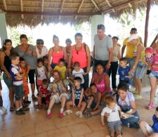 Actividad asistida con animales. La facilitadora Lic. Rocío Fernández rodeada por un grupo de niños y familiares